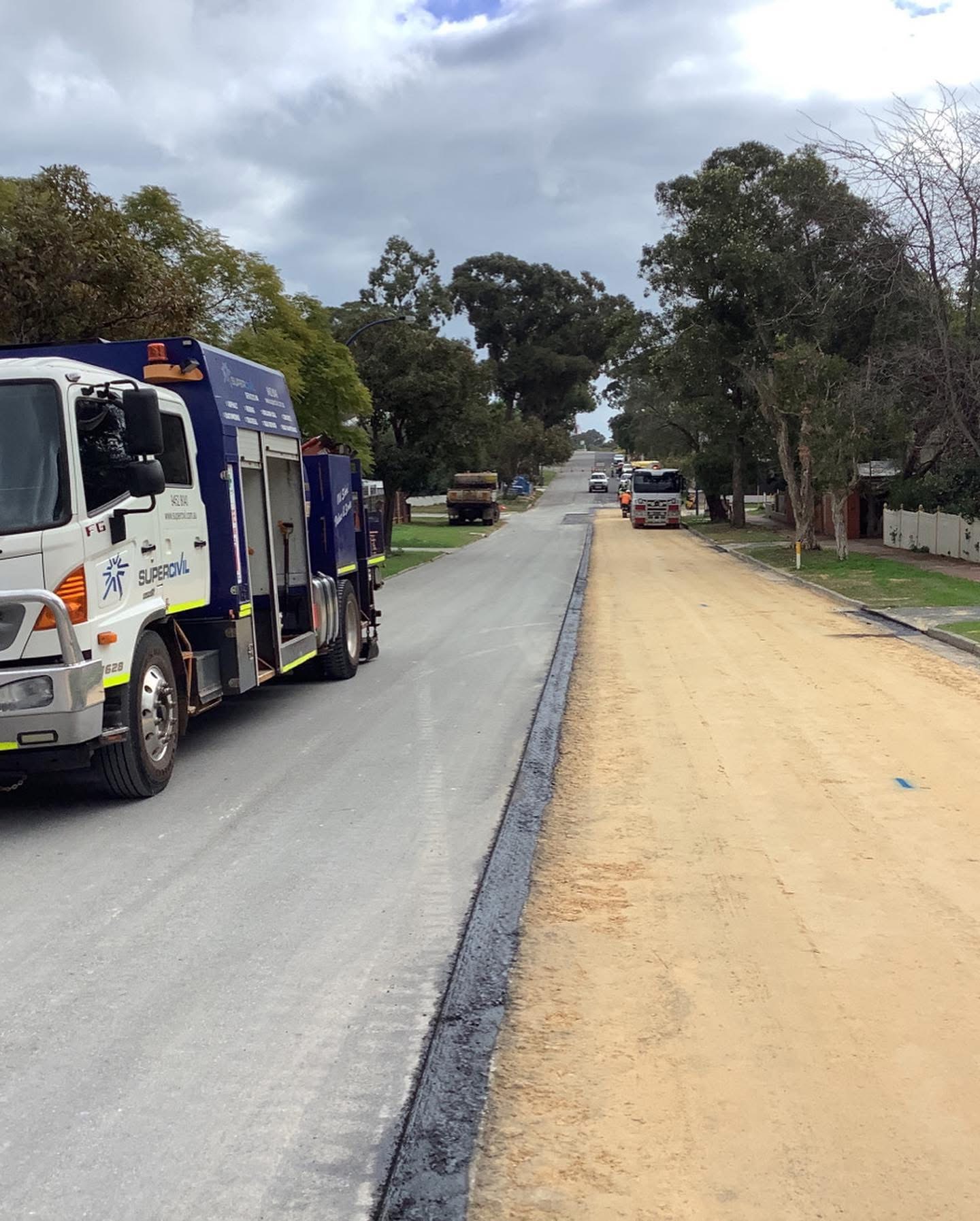 SuperCivil service truck parked on a suburban Perth street during road reconstruction, with one lane freshly sealed in new asphalt and the other stripped back to sand base