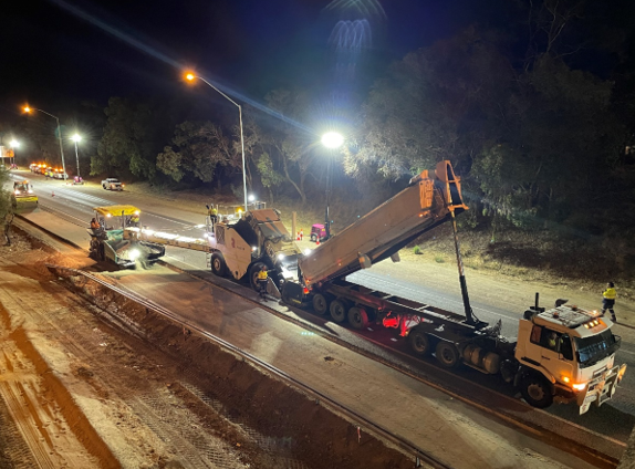 SuperCivil crew and asphalt paving machinery working under floodlights on a night-time Western Australian highway resurfacing project